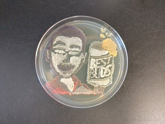 a petri dish with a bacteria drawing of person from the shoulders up holding a bubbling can labeled Best Buds